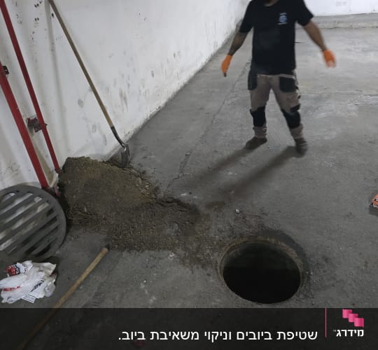 עבודת ניקוי סביב פתח ביוב עם כלי עבודה ואדם